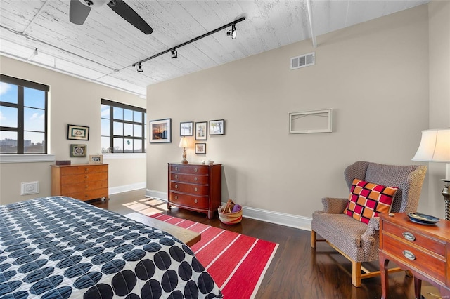 bedroom with baseboards, rail lighting, wood finished floors, and a ceiling fan