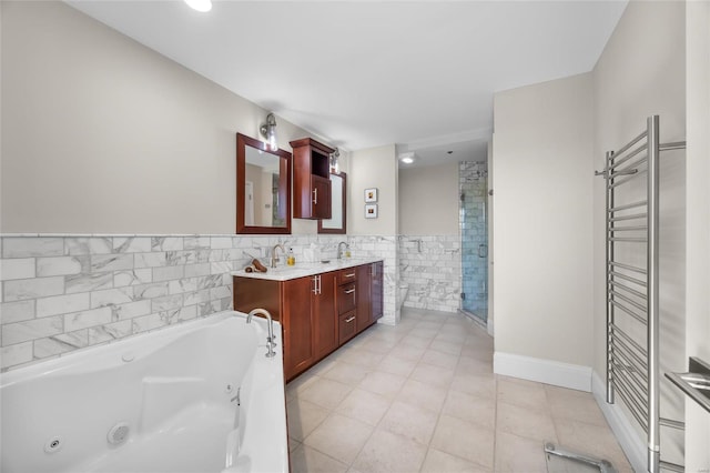 bathroom with a whirlpool tub, a stall shower, a towel warming rack, double vanity, and tile walls