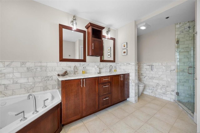 bathroom featuring tile walls, double vanity, toilet, a garden tub, and a shower stall