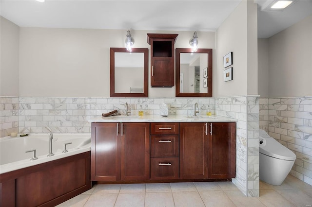 bathroom with tile walls, tile patterned flooring, a bath, a wainscoted wall, and double vanity