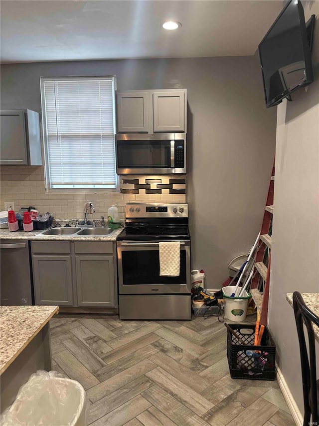 2803 Semple Ave, Saint Louis, MO 63120 - kitchen featuring stainless steel appliances, a sink, light countertops, tasteful backsplash, and gray cabinetry