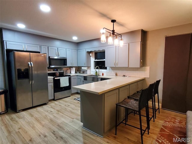1028 County Road 606, Cape Girardeau, MO 63701 - kitchen with appliances with stainless steel finishes, a peninsula, light wood finished floors, a sink, and light countertops