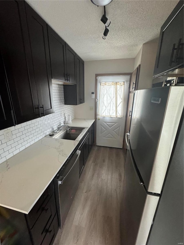 9 Summit Ln, Hermann, MO 65041 - kitchen featuring appliances with stainless steel finishes, light wood-type flooring, dark cabinets, tasteful backsplash, and a textured ceiling