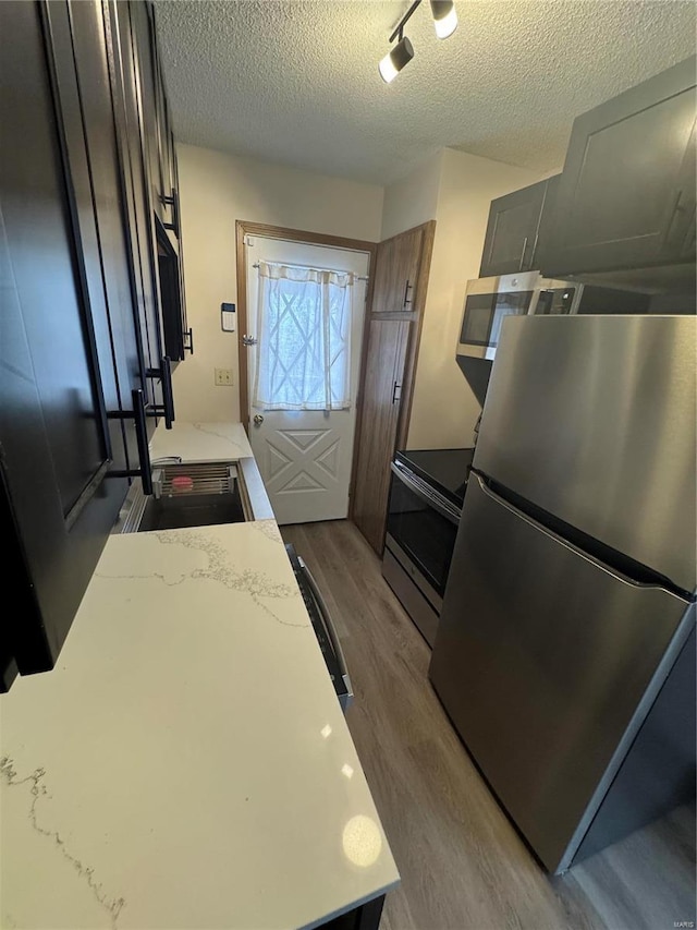 9 Summit Ln, Hermann, MO 65041 - kitchen featuring appliances with stainless steel finishes, wood finished floors, a textured ceiling, and light stone counters