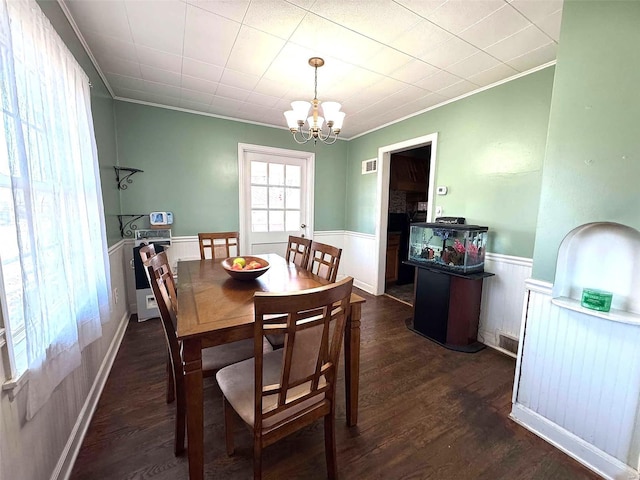 dining area featuring a chandelier, a wainscoted wall, wood finished floors, and crown molding