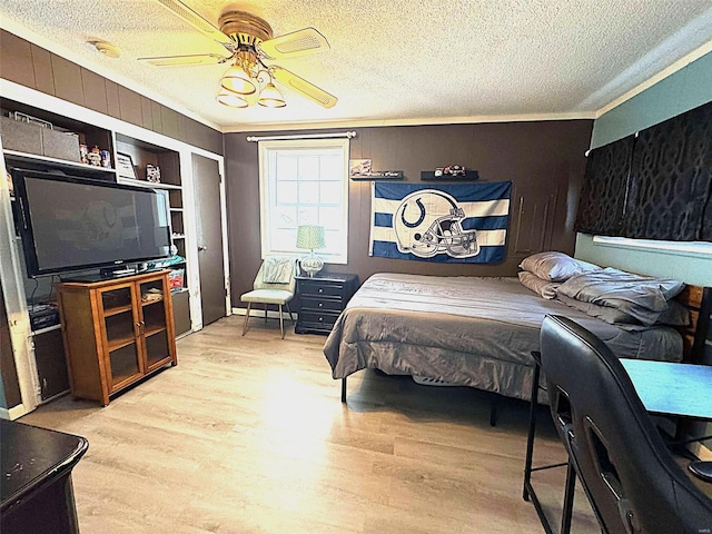 bedroom with wood finished floors, a textured ceiling, crown molding, and a ceiling fan