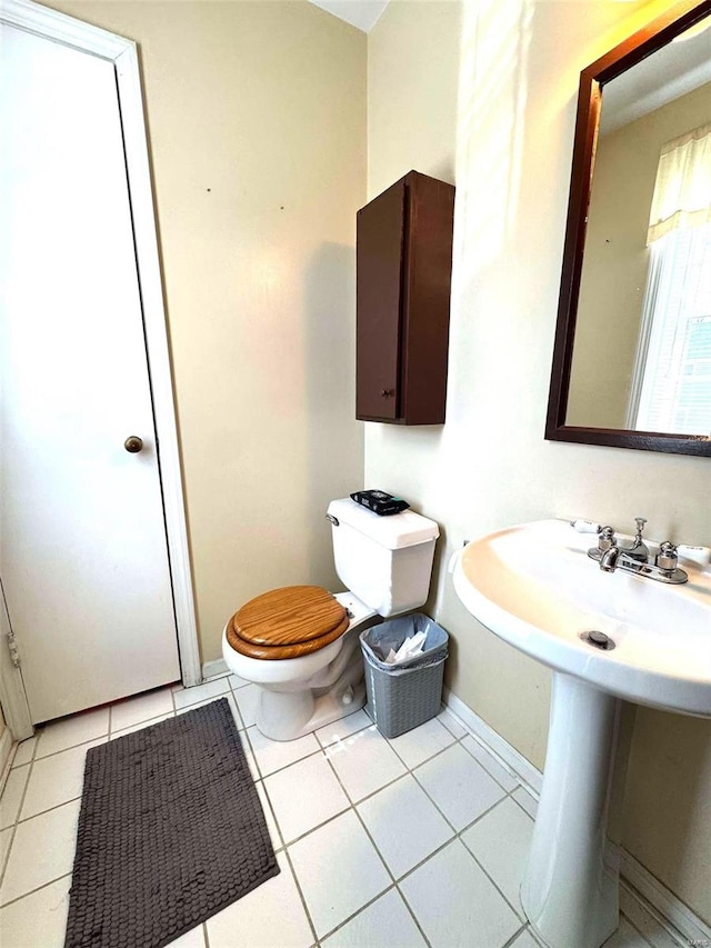 bathroom featuring toilet, baseboards, tile patterned flooring, and a sink