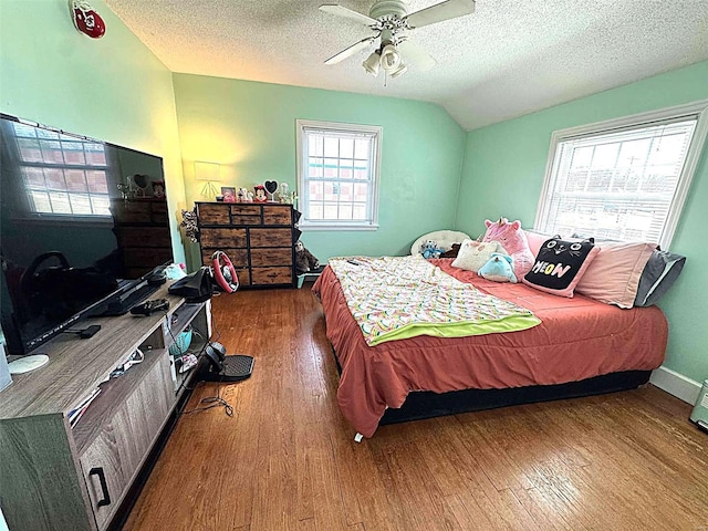 bedroom with wood finished floors, lofted ceiling, a textured ceiling, ceiling fan, and baseboards