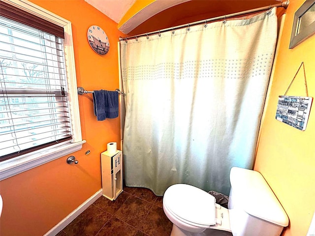bathroom with toilet, tile patterned flooring, baseboards, and curtained shower
