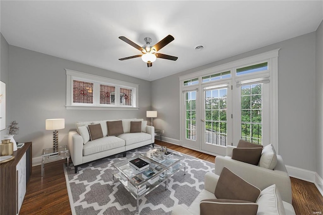 living area featuring ceiling fan, baseboards, and dark wood finished floors