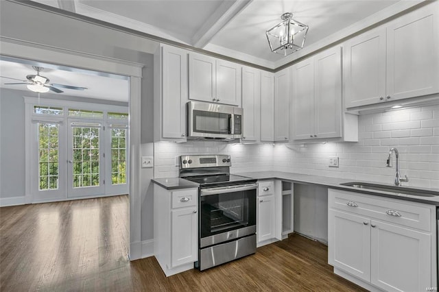 kitchen with appliances with stainless steel finishes, a sink, dark wood-type flooring, tasteful backsplash, and beamed ceiling