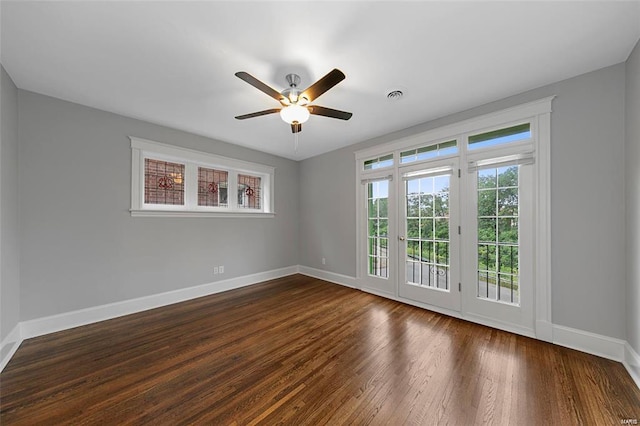 unfurnished room featuring baseboards, dark wood-style flooring, and a ceiling fan