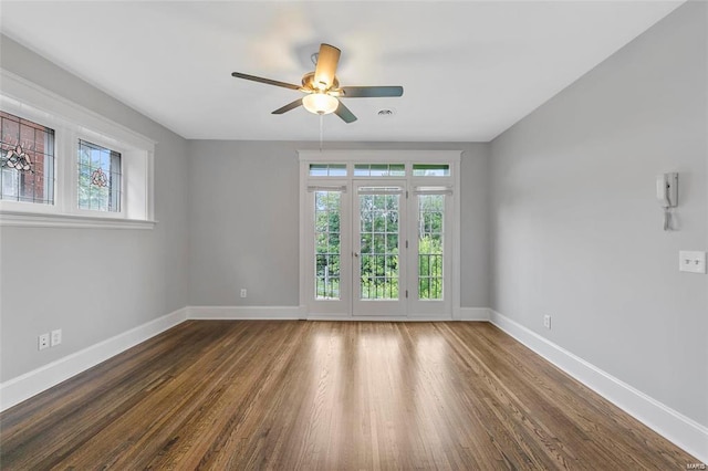 unfurnished room featuring healthy amount of natural light, baseboards, and wood finished floors