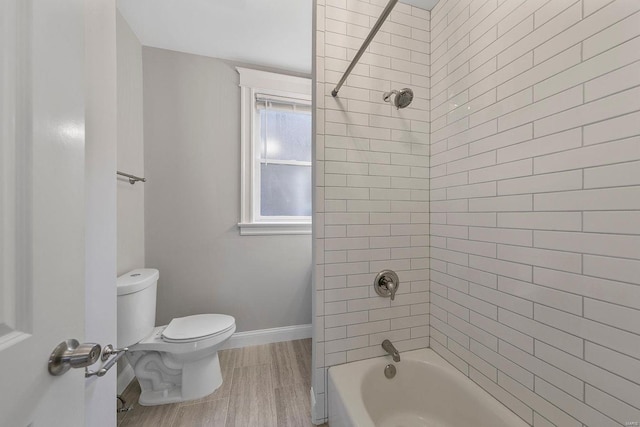 bathroom featuring toilet, washtub / shower combination, baseboards, and wood finished floors