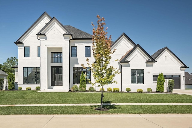 french country style house featuring a front lawn, a garage, brick siding, driveway, and french doors