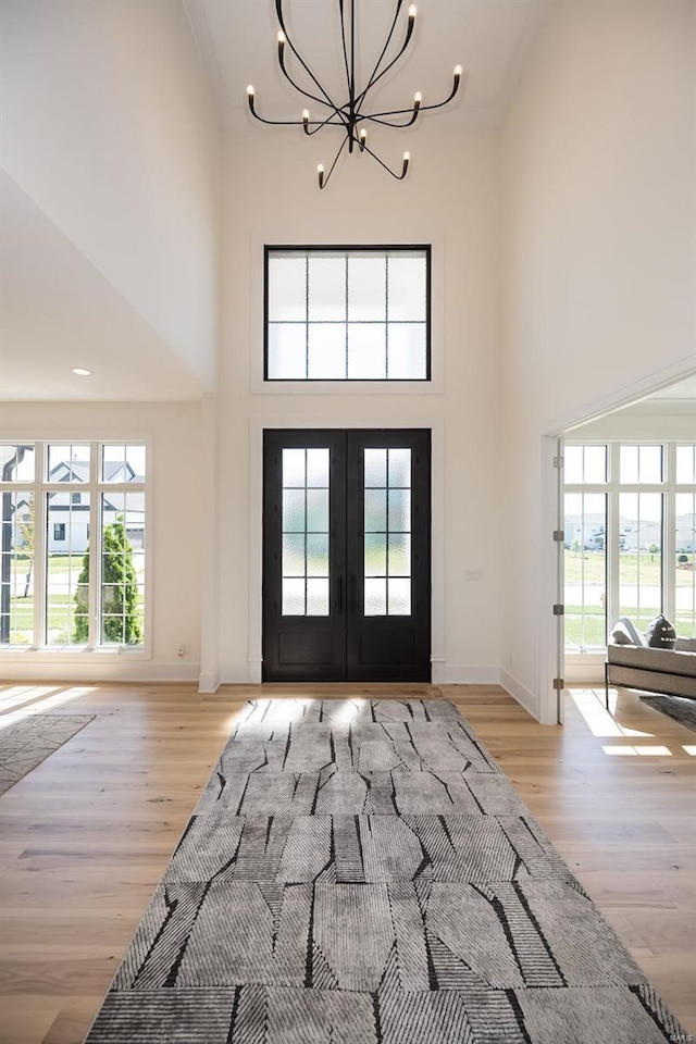 foyer entrance featuring a chandelier, a high ceiling, french doors, healthy amount of natural light, and light wood-style floors