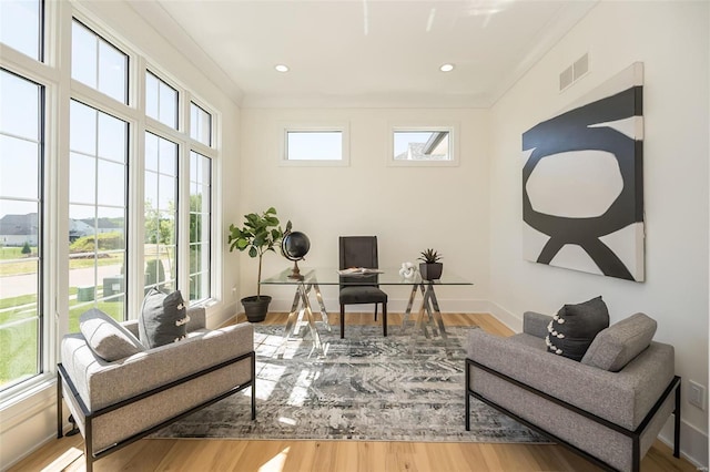 living area with wood finished floors, ornamental molding, a desk, and baseboards