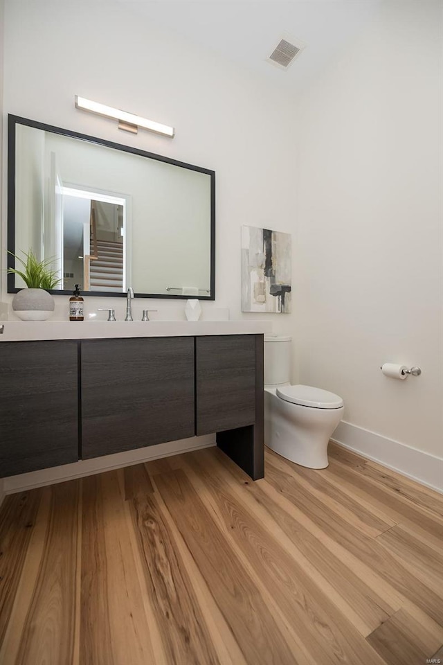 bathroom featuring toilet, wood finished floors, vanity, and baseboards