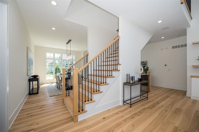 staircase with wood finished floors, recessed lighting, a chandelier, and baseboards