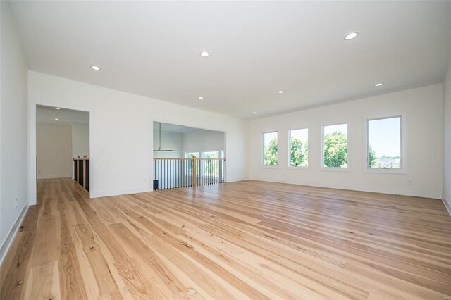 unfurnished living room with recessed lighting, light wood-style flooring, and baseboards