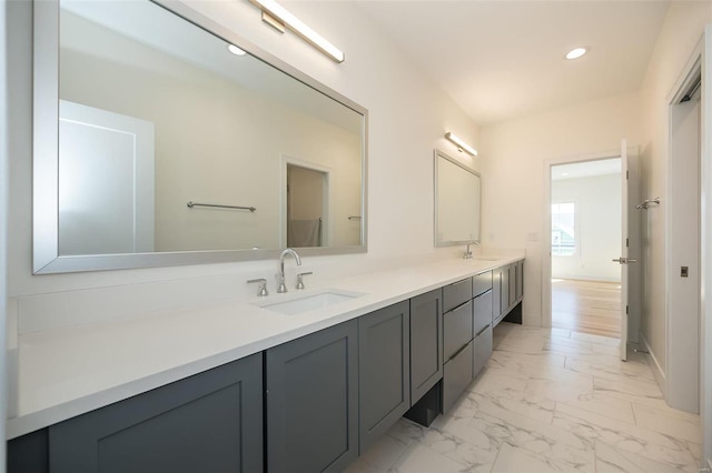 bathroom featuring marble finish floors, double vanity, and recessed lighting