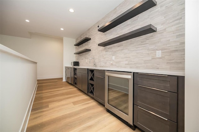 indoor wet bar featuring beverage cooler, decorative backsplash, baseboards, recessed lighting, and light wood-style flooring
