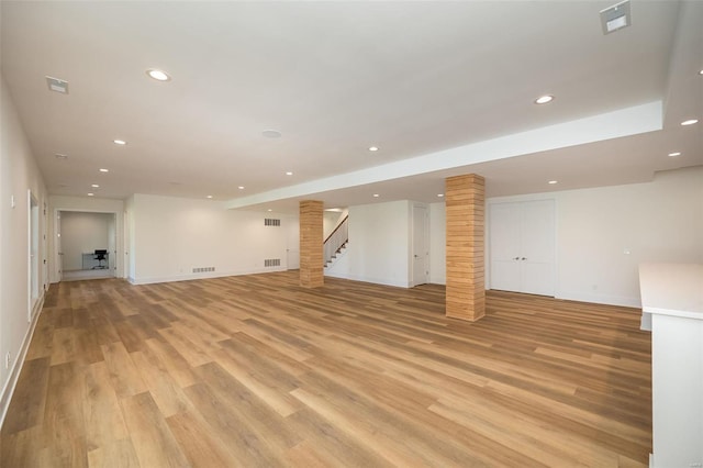 finished below grade area featuring recessed lighting, baseboards, light wood-style floors, and stairs