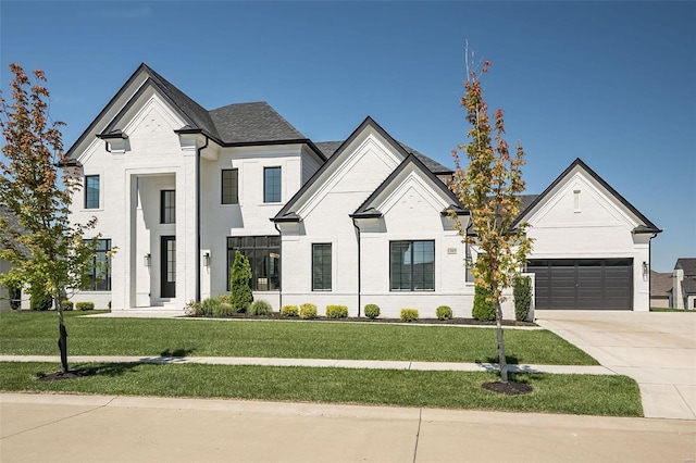 french country home with concrete driveway, a front lawn, brick siding, and an attached garage