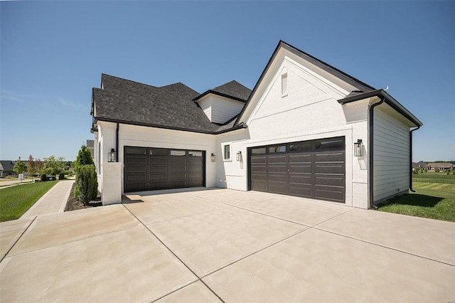view of front of home with concrete driveway, an attached garage, and a shingled roof