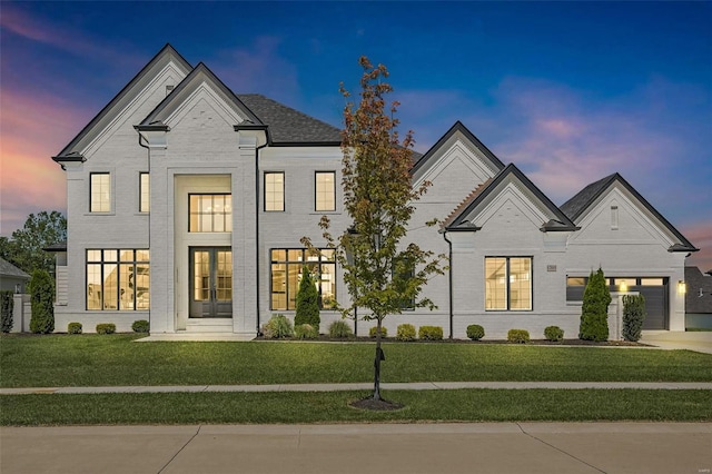 french country style house featuring a yard and brick siding