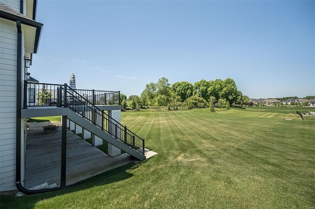 view of green lawn with stairs and a wooden deck