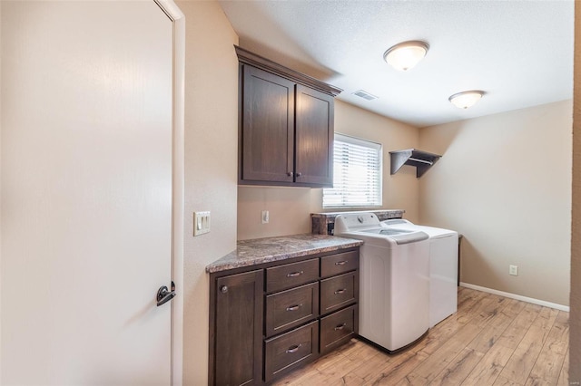 laundry area featuring washer and clothes dryer, cabinet space, light wood finished floors, and baseboards