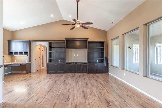 unfurnished living room featuring ceiling fan, arched walkways, light wood finished floors, lofted ceiling, and baseboards