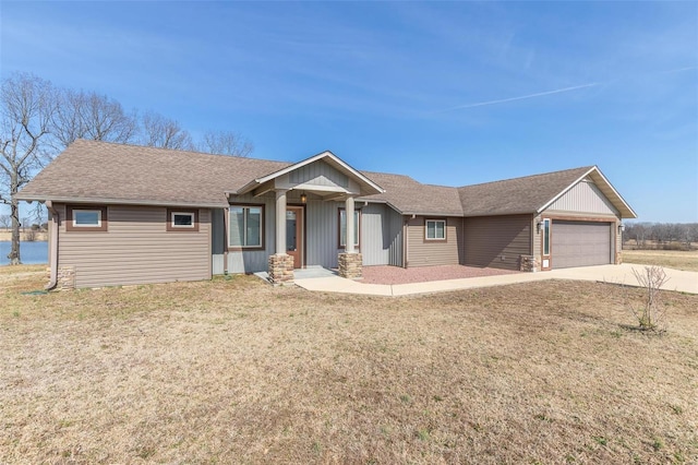 view of front of home with a garage, driveway, a front yard, roof with shingles, and a porch