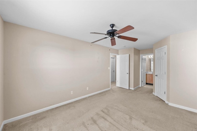 unfurnished bedroom featuring baseboards, light colored carpet, connected bathroom, and a ceiling fan