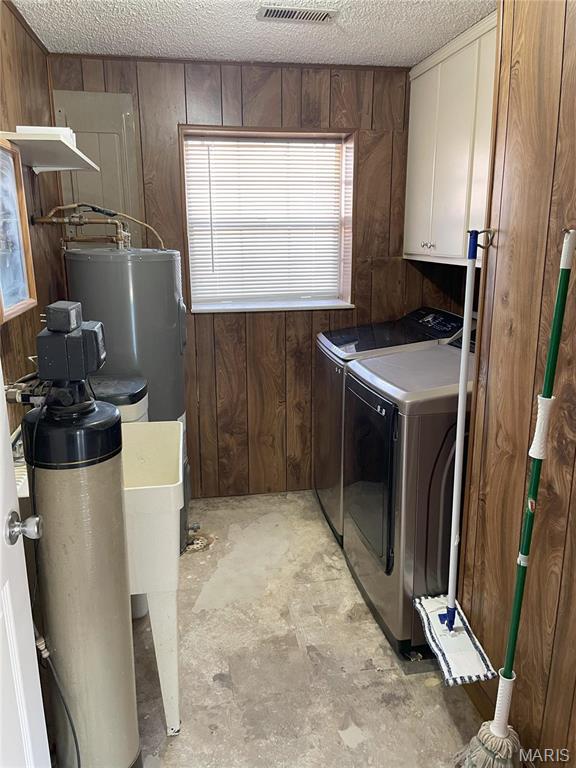 1770 Pigg Hollow Rd, Owensville, MO 65066 - washroom featuring wood walls, gas water heater, a textured ceiling, washing machine and dryer, and plenty of natural light