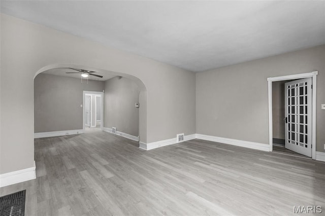 6040 Maple Ave, Saint Louis, MO 63112 - spare room featuring arched walkways, ceiling fan, wood finished floors, and baseboards