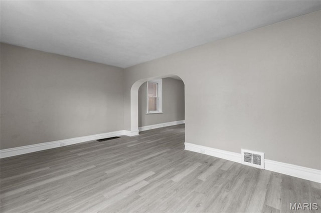 6040 Maple Ave, Saint Louis, MO 63112 - unfurnished room with arched walkways, wood finished floors, and baseboards