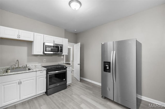 6040 Maple Ave, Saint Louis, MO 63112 - kitchen featuring appliances with stainless steel finishes, a sink, light wood finished floors, baseboards, and white cabinetry