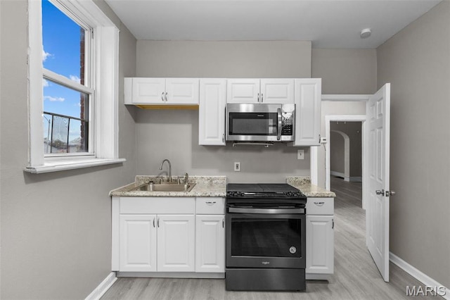 6040 Maple Ave, Saint Louis, MO 63112 - kitchen featuring stainless steel microwave, gas range, a sink, light wood-type flooring, and baseboards