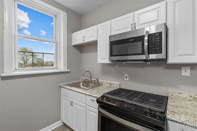 6040 Maple Ave, Saint Louis, MO 63112 - kitchen with stainless steel microwave, gas stove, a sink, and white cabinetry
