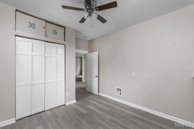 6040 Maple Ave, Saint Louis, MO 63112 - unfurnished bedroom with wood finished floors, baseboards, a closet, and a ceiling fan