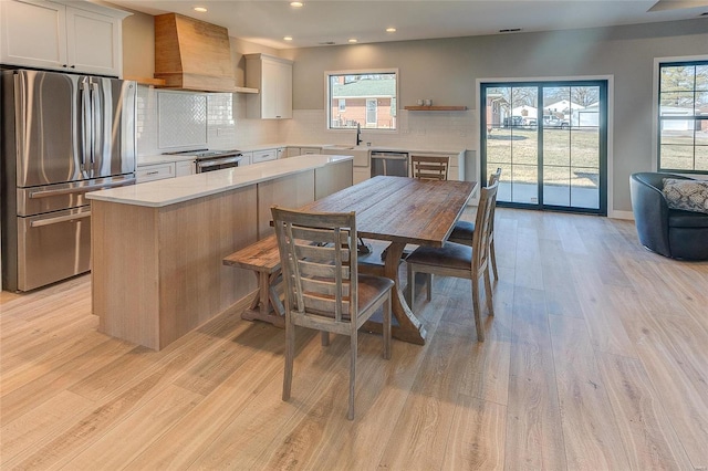 115 S Taylor St, Red Bud, IL 62278 - kitchen featuring appliances with stainless steel finishes, wall chimney exhaust hood, light wood-type flooring, tasteful backsplash, and recessed lighting