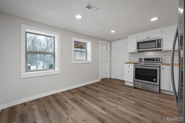 700 W Main St, Union, MO 63084 - kitchen with appliances with stainless steel finishes, a textured ceiling, plenty of natural light, white cabinetry, and backsplash