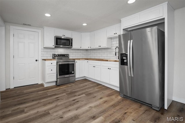 700 W Main St, Union, MO 63084 - kitchen featuring stainless steel appliances, butcher block counters, white cabinets, dark wood-type flooring, and backsplash