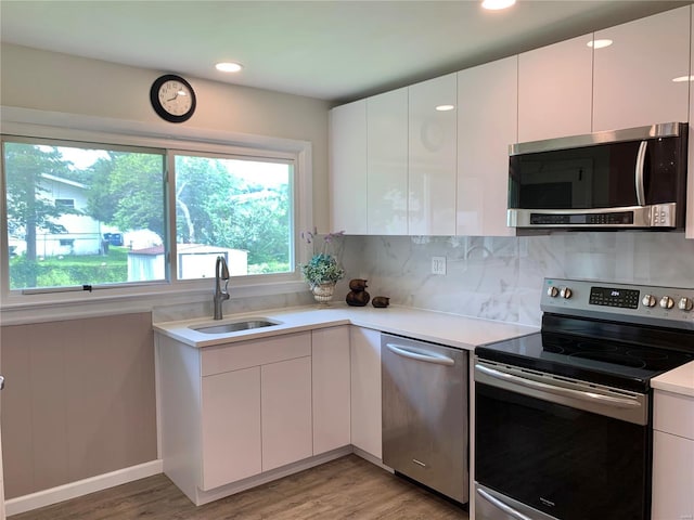2903 Lesmer Ct, Overland, MO 63114 - kitchen featuring appliances with stainless steel finishes, a sink, modern cabinets, light countertops, and white cabinetry