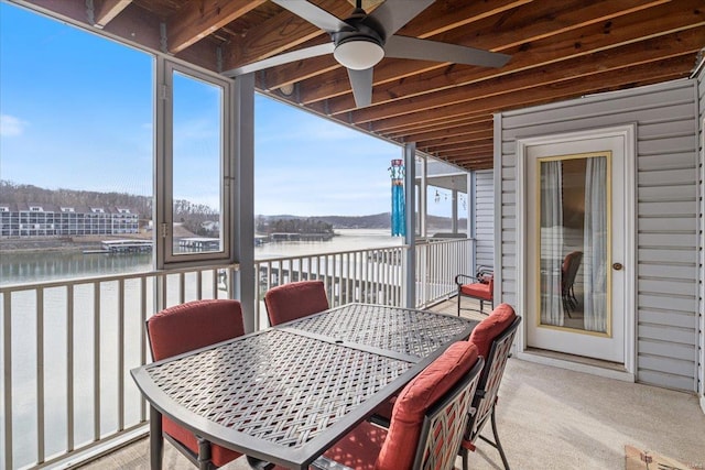 sunroom / solarium with a water view, a ceiling fan, and carpet flooring