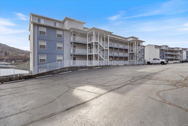 view of apartment building / complex with uncovered parking and fence
