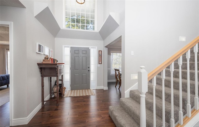 foyer with wood-type flooring, baseboards, stairway, and a towering ceiling
