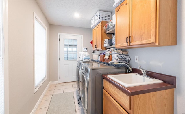washroom featuring washer and clothes dryer, cabinet space, light tile patterned floors, a textured ceiling, and baseboards